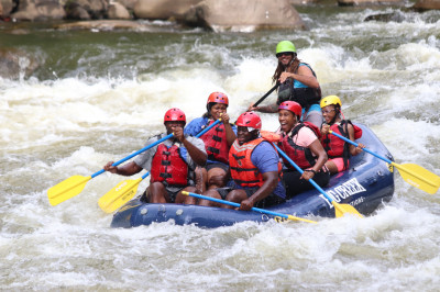 Five People and Their Guide Paddle Through Powerhouse Rapid  a Class Iii on the Whitewater Rafting Trip